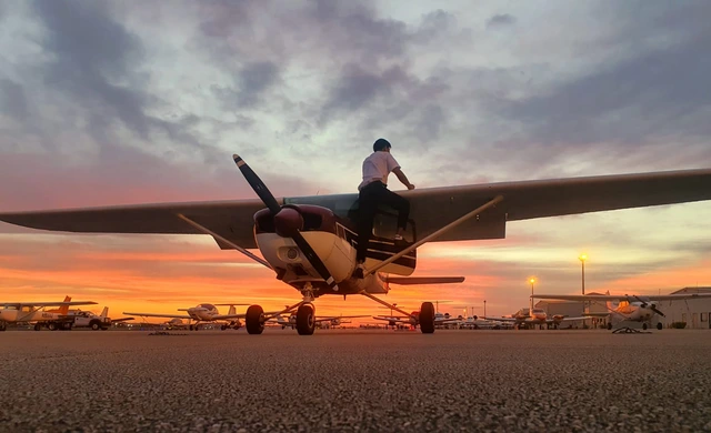 Stavan beside an aircraft at sunset.