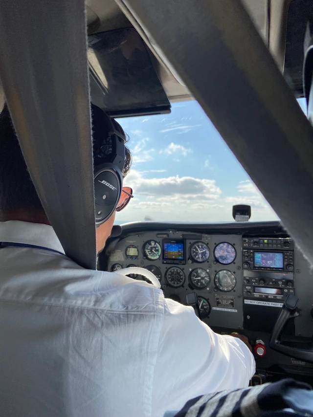 An over-the-shoulder view of Stavan wearing a headset in the cockpit.