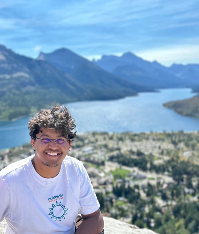 Stavan smiling beside a lake and mountains.